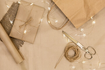 Preparing for Christmas and New Year. Eco-friendly materials for wrapping gifts. Scissors, rope, kraft paper on linen fabric. Monochrome photo, top view