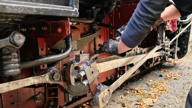 Mechanic adding oil in mechanisms of stopped steam train Mocanita at a railway station, Romania