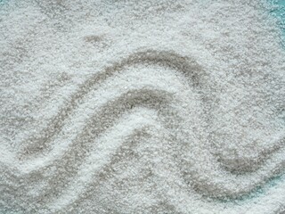 Sea salt scattered on a blue background, texture waves top view. Salt cave concept. Salt for the treatment of the respiratory tract