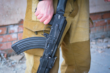 A man in overalls holds a Kalashnikov assault rifle in his hand, close-up. Small arms of Russia.