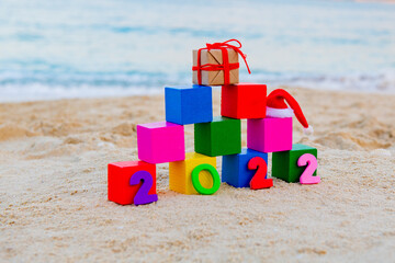 Colored cubes on the beach 2022 numbers lie on the sand next to gifts