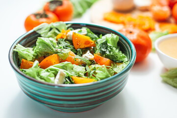 Light sweet and sour salad with persimmon, tangerines and cheese. Winter vitamin salad and ingredients on a White table. Diet food. Selective focus