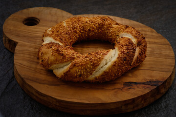 Traditional turkish bagel on a dark stone surface. Simit on cutting board. Sesame encrusted pastry