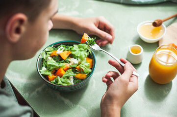 Vegan breakfast or lunch. Teen boy eating breakfast Winter vitamin salad on white table with a...