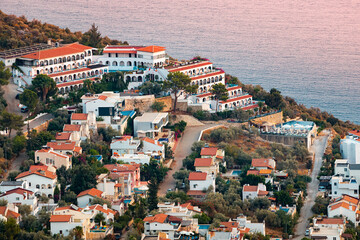 Sunset aerial view of seashore resort town on mediterranean coast. Romantic harbour and villas with red roofs waiting for vacationers