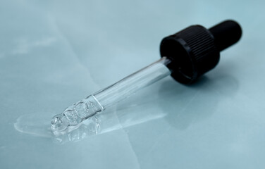 Pipette with fluid hyaluronic acid on gray background. Cosmetics and healthcare concept closeup. Dose of serum or retinol with air bubbles. Flat lay. Luxury gel or beauty product presentation in macro