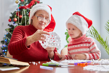 surprised girl looks at her grandmother's crafts for the new year and Christmas. Santa's hat as a symbol of Christmas