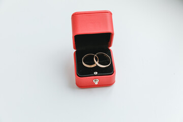 Two beautiful wedding rings on red jewelry box on white background. Declaration of love Wedding card Valentine's Day greeting. Wedding rings. Wedding day details