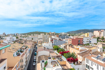 Obraz premium View from the heights of neighboring houses, with a road with cars and flowering plants between the houses, on the horizon you can see mountains