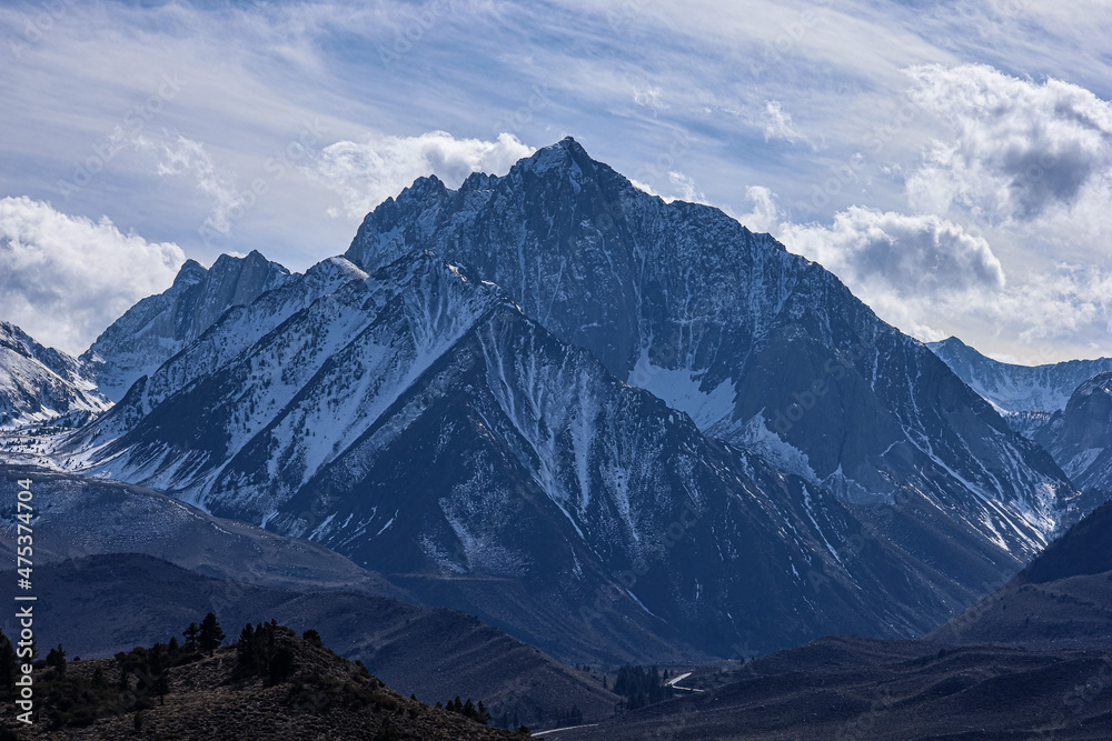 Poster Scenic view of a rocky mountain enveloped in the snow on a cloudy sky background