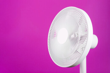 Electric fan in white with a modern design for cooling the room on a pink background.