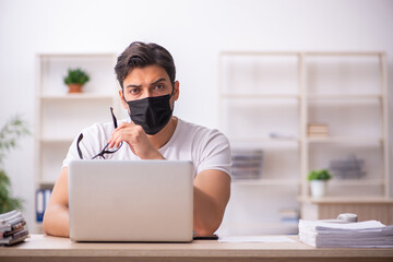 Young male student employee working at workplace during pandemic