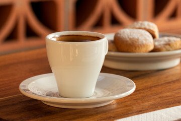 Primer plano de taza de café espresso con galletas al fondo