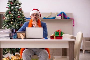 Fototapeta premium Young businessman working from home at Christmas eve