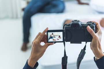 Mother is photographers are shooting African family relaxing on white bed in bedroom, To get a...