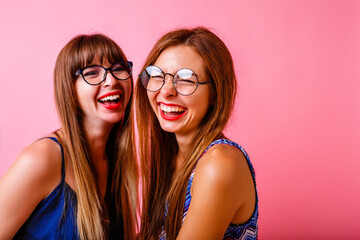 Couple of happy positive beat friends sister girls posing at studio pink background