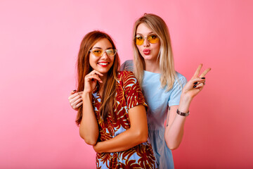 Studio portrait of two positive best friend women having fun at pink background