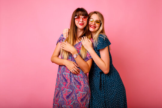 Studio portrait of two positive best friend women having fun at pink background