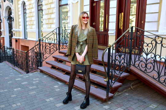 Outdoor fashion image of stunning blonde model woman posing on the Paris street