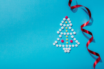 Creative Christmas tree made of pills on a blue background. Holiday greeting card with space for text.