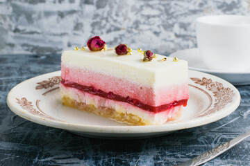 Delicious mousse cake on vintage plate, spoon and espresso in white cup on gray background