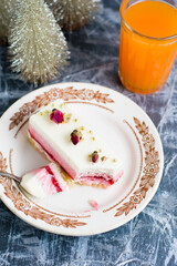 Sweet mousse cake on vintage plate flatlay and decorative christmas tree and glass of juice on gray background