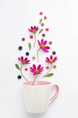 Composition of berries and flowers over a cup.