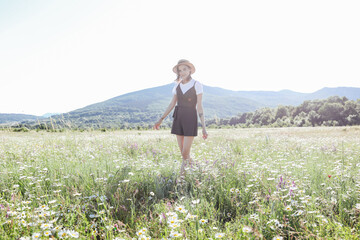 a beautiful woman walks in a field with chamomile flowers