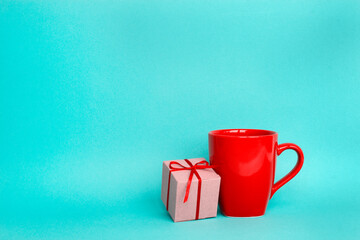 Red cup and gift box on a blue background. A blank for a Christmas composition. Copy space. - 475383379