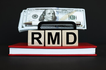 RMD Required Minimum Distribution. text on wooden cubes. On a black background. red notepad. Money