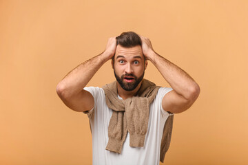 Human face expressions and emotions. Caucasian young adult man holding arms on his head and feeling...