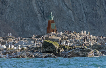 Penguins and bust of Captain Luis Pardo Villalon on the beach, Point Wild, Elephant Island,...