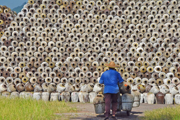 Man pushing cart loaded with wine jars to the big pile in a winery, Zhejiang Province, China