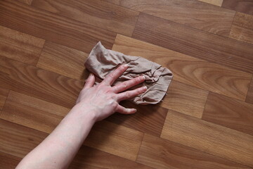 Woman's hand washes the parquet floor with a rag
