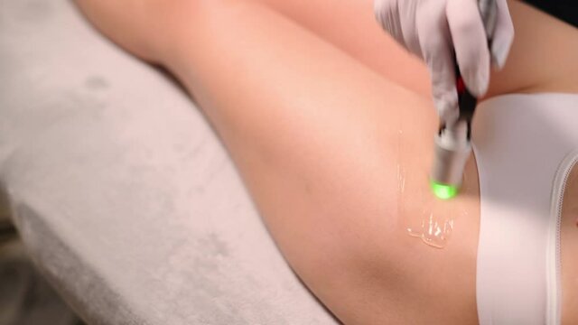Professional cosmetologist doing laser hair removal of bikini area to young woman in beauty salon. Close up.