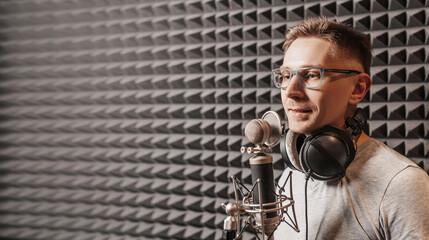 The vocalist sings in the studio in a microphone. Man in headphones writes a podcast, an audiobook....