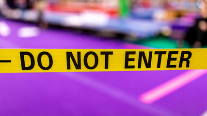 Wide yellow ribbon with writing "DON NOT ENTER" on it against purple background
