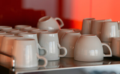 A lot of empty clean cups used for coffee drinks are placed on a table and are ready to be served.