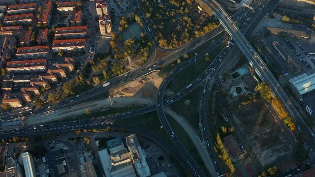 High angle view of busy multilane multilevel highway interchange in town. Heavy traffic on trunk road in rush hours. Evening golden hour.