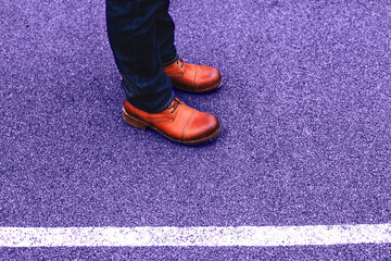 A man in brown handmade leather boots. Men's shoes on a brown background on the road trend color of year