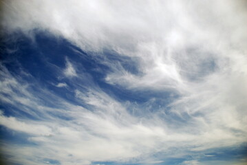 White cirrus clouds over the sky. The light blue sky is flooded with the sun, high white cirrus clouds float across the sky. They stretched out over great distances.
