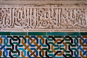 Alhambra, Detailed background of the Alhambra Palace with intricate tile patterns on the wall and arabic writing in the middle. Ceramic wall.Granada, Spain ,Andalusia - obrazy, fototapety, plakaty
