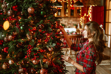 beautiful young woman in red pajamas decorate Christmas tree in living room for celebration of Christmas and New Year