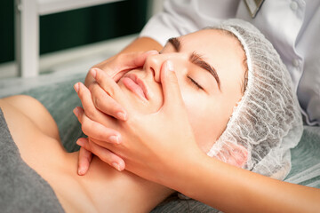 Obraz na płótnie Canvas A young caucasian woman getting facial massage in a spa