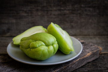 Fresh green prickly pumpkin, chayote on wooden background, (Sechium edulis)