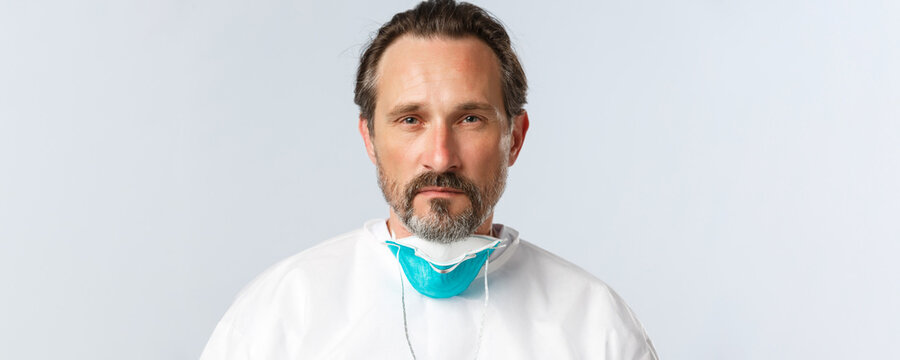 Covid-19, Virus, Healthcare Workers And Vaccination Concept. Close-up Of Serious-looking Tired Doctor Take-off Medical Respirator And Looking Camera Determined, Finish Shift With Coronavirus Patients