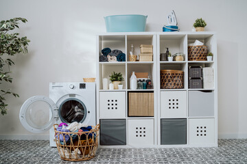 View of home laundry room, dresser with softeners, powder, towels, open washing machine with empty...