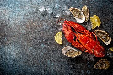 Boiled cooked red whole lobster ready to eat and fresh open oysters served with lemon wedges and...