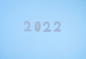 Happy New Year 2022. Christmas background with silver glittering numbers 2022 on light blue background. View from above. Place for your text.