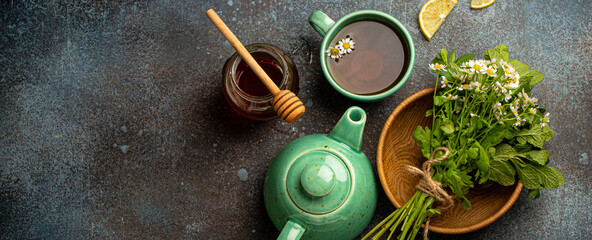 Herbal tea with fresh medical herbs and flowers, tea cup, tea pot and bouquet of fresh wild flowers...